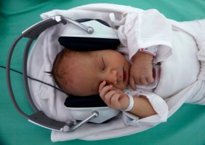 A newborn baby rests in a box, listening to music played through earphones in Saca Hospital in Kosice